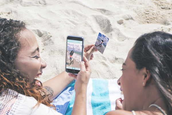 Women on beach viewing Lifeprint photo - Lifeprint photo printer for iPhone and Android